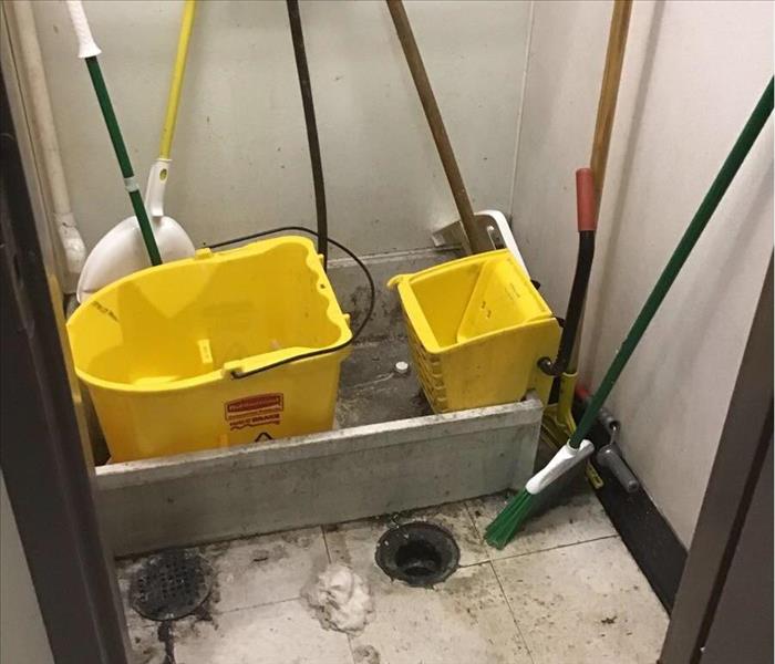 back work room cleaning floor sink full of mops and buckets