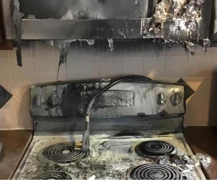 A stove with ashes and soot all over it from being caught on fire.  